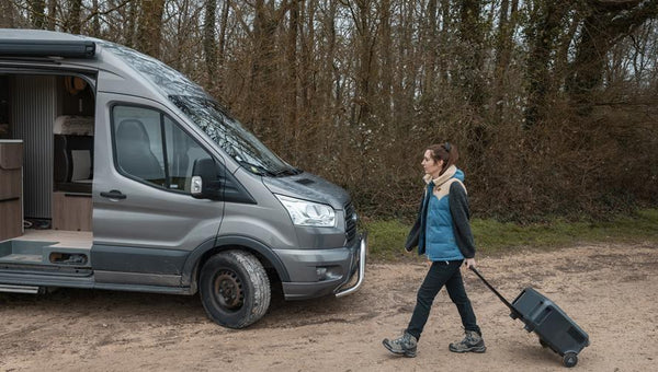 Donna trasporta un generatore portatile accanto al camper