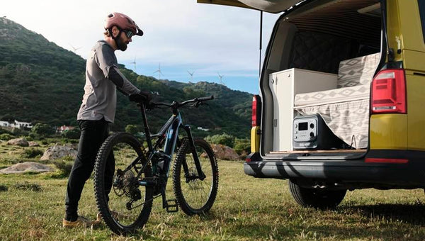 Ciclista accanto al camper con generatore solare portatile
