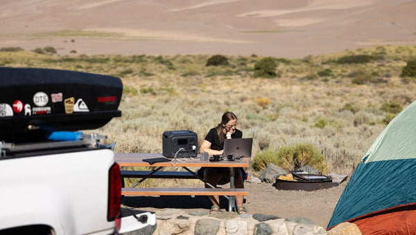 Donna lavora al computer con power station in campeggio
